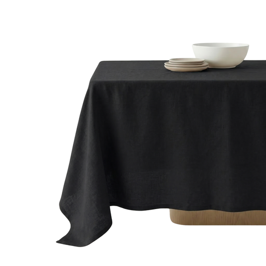 Black tablecloth on a round table with white bowls and plates.