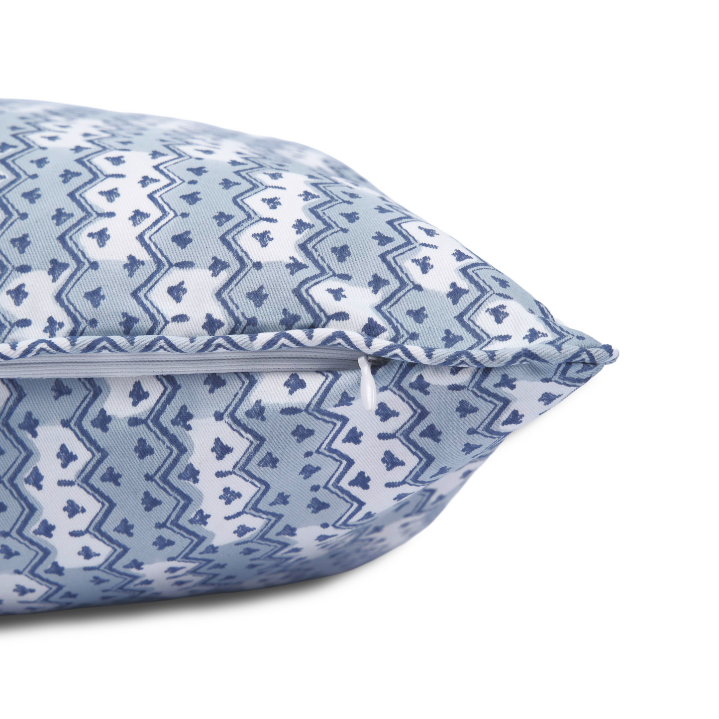 A close-up side view of the hand-block printed Munnar Frost cushion lying flat on a white background. This shot highlights the neatly sewn, discreet hidden zipper closure and the light blue and white geometric zig-zag pattern. This handcrafted textile perfectly adds a cozy modern rustic Canadian farmhouse aesthetic to your home decor.