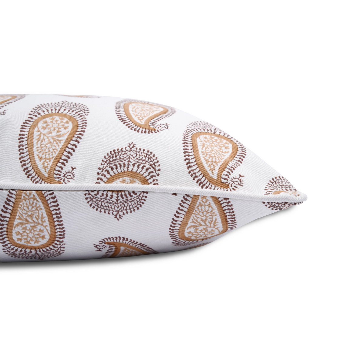 A close-up side view of a hand-block printed cushion featuring a warm ochre and earthy brown classic paisley pattern on a cream background. This detail shot highlights the neatly finished piped edge, showcasing the quality of this handcrafted textile that perfectly adds a cozy modern rustic Canadian farmhouse aesthetic to any home decor.