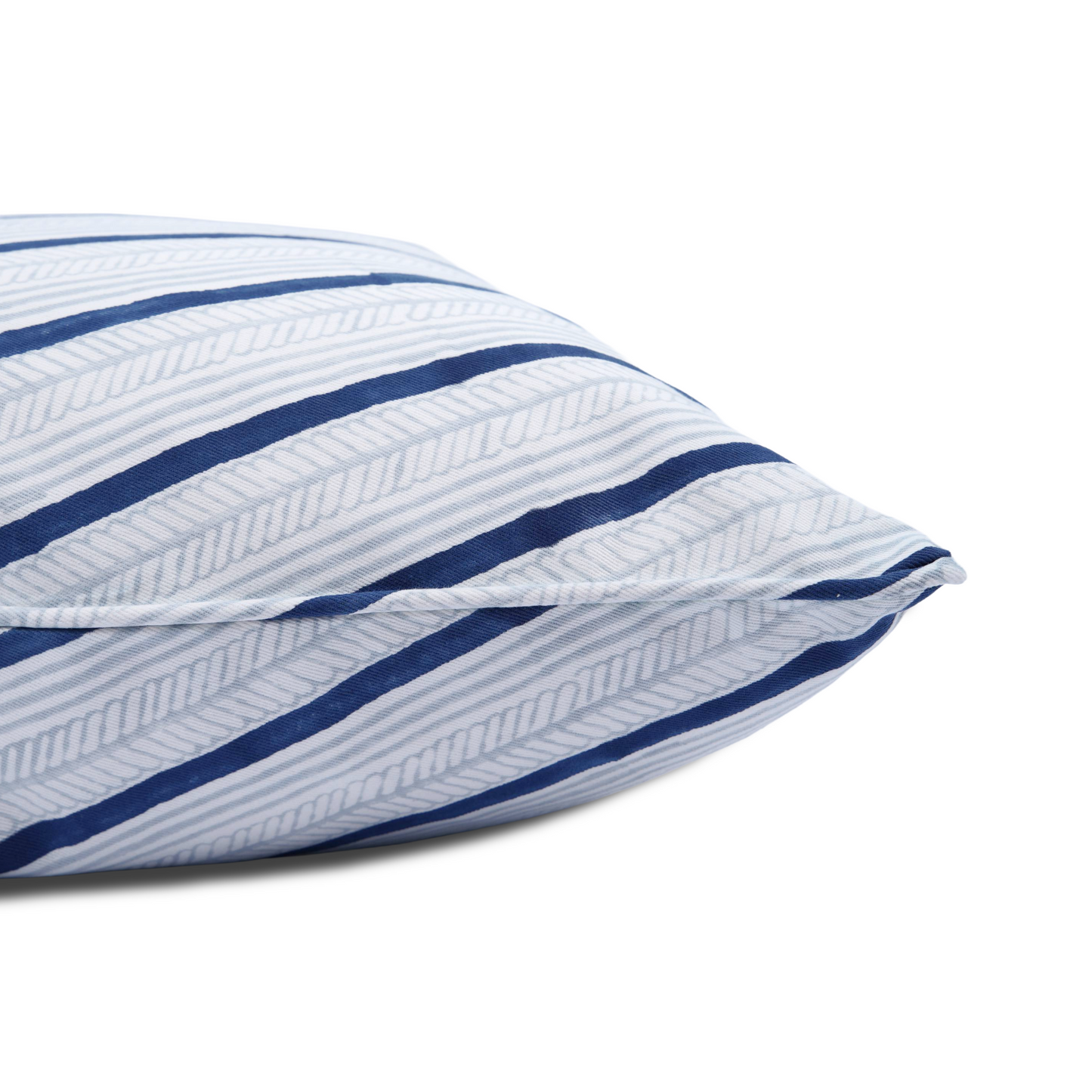 A close-up side view of the hand-block printed Serere Frost cushion lying flat on a white background. This detailed shot highlights the neatly sewn edge and the dynamic diagonal pattern of bold indigo stripes alternating with soft, textured light blue lines. This handcrafted textile adds a crisp, cozy modern rustic Canadian farmhouse aesthetic to your home decor.