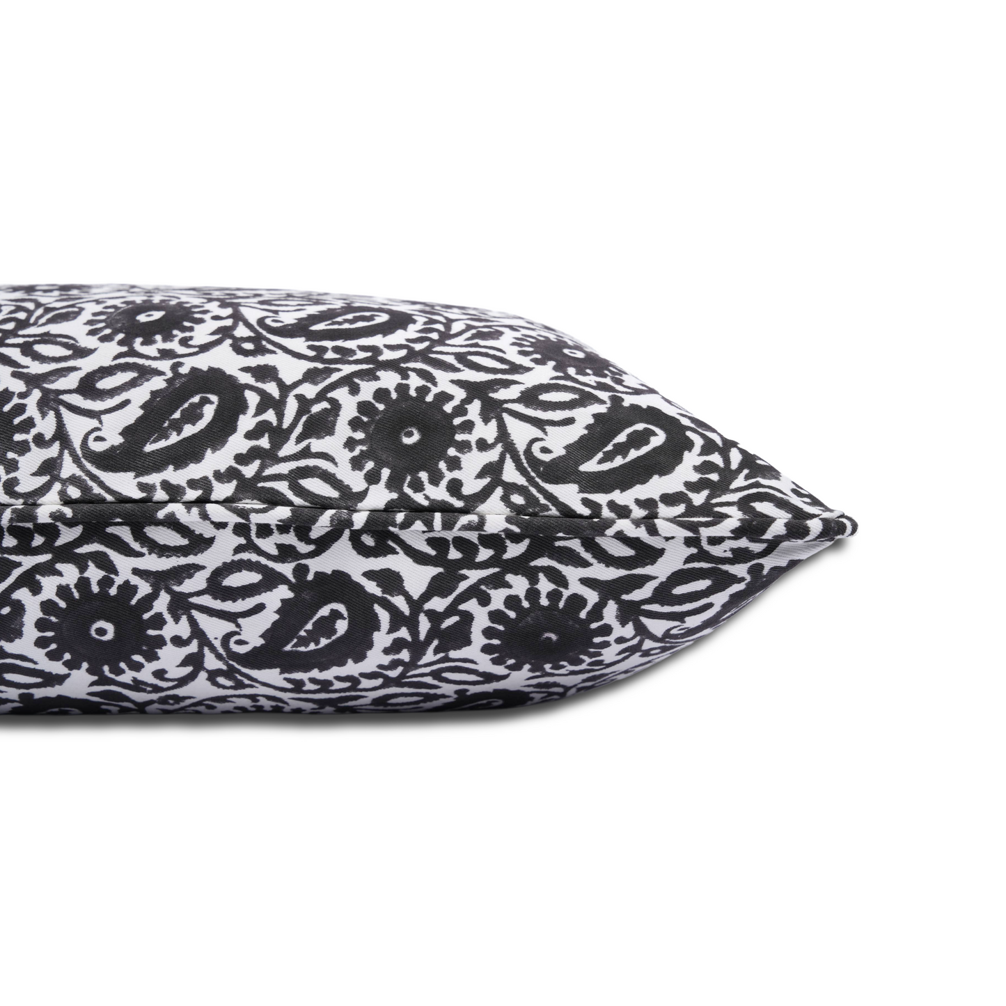 Side-profile close-up of the Siona Charcoal 100% cotton block printed pillow cover resting against a clean white background. Highlights the tailored piped edge seam and bold charcoal black and white floral paisley print. Fine handmade artisan textile home decor.