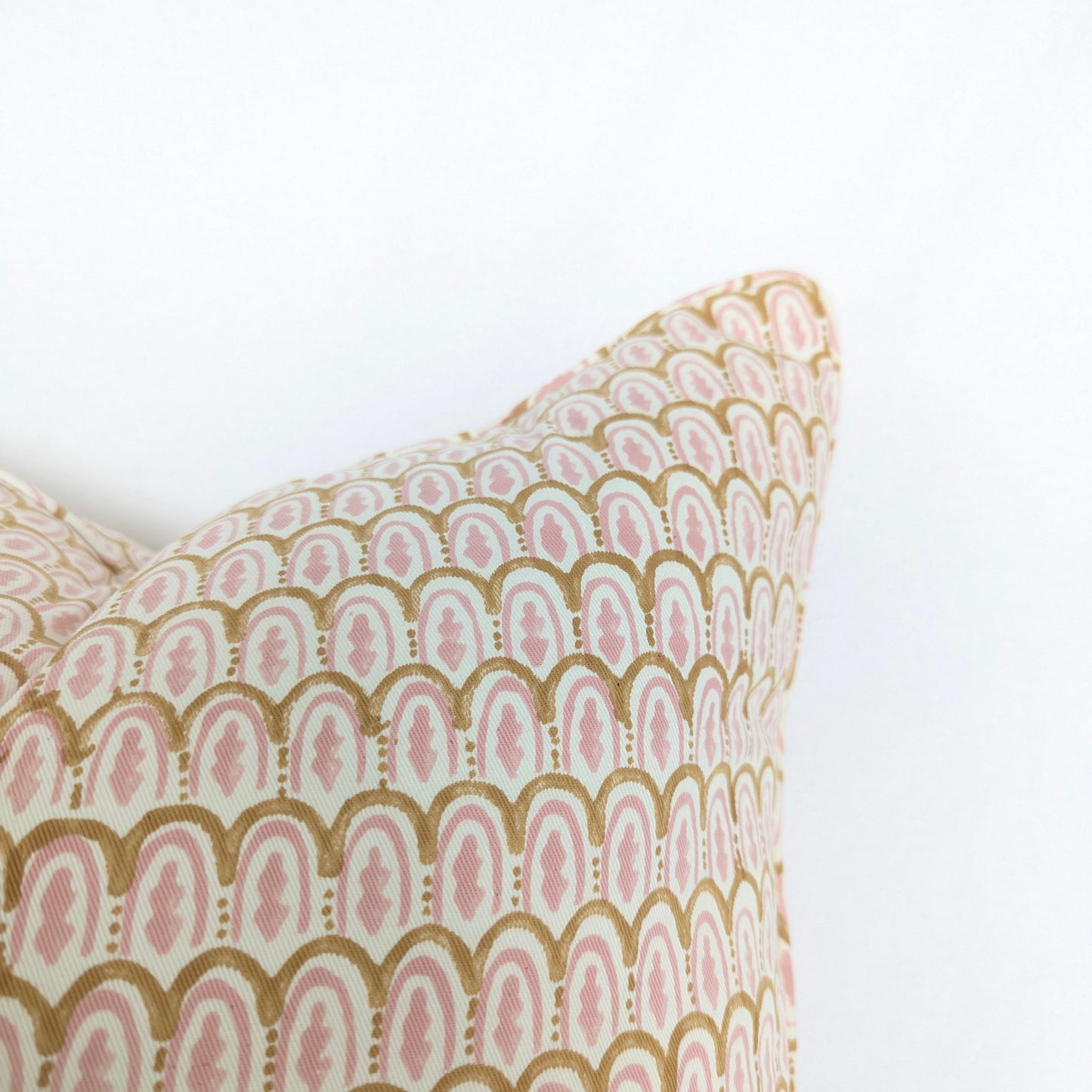 Decorative pillow with pink and gold geometric pattern on a white background
