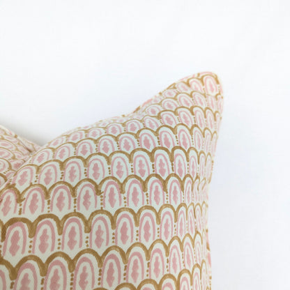 Decorative pillow with pink and gold geometric pattern on a white background