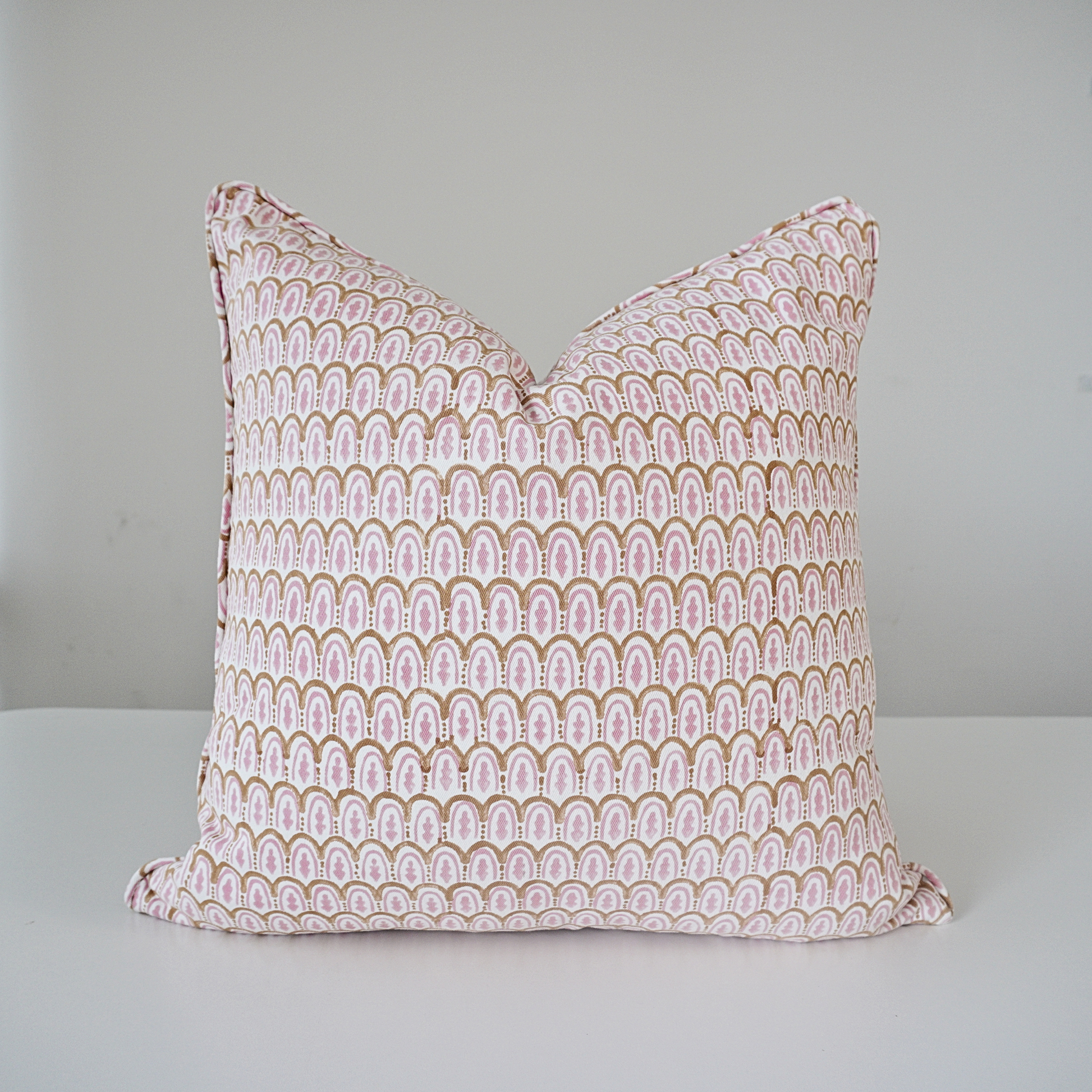 Square Bikaneri Topaz 100% cotton block printed pillow cover. This artisan throw cushion features a repeating hand-stamped scalloped arch pattern in soft pink and golden tan on a crisp white background. Beautiful handmade textile home decor.