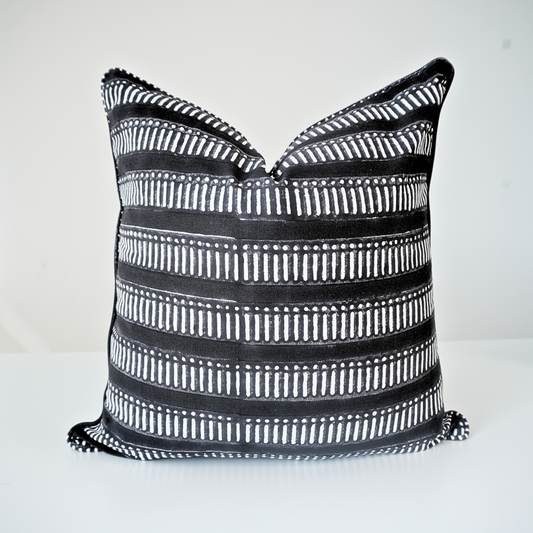 Studio product shot of a single Eko Charcoal cushion cover by Homeway Living. Handmade from 100% cotton, this block-printed pillow features a bold black base with white horizontal geometric stripes. Finished with tailored piped edges, it offers a clean, high-end aesthetic perfect for modern rustic or Scandinavian home styling in Canada and the US.