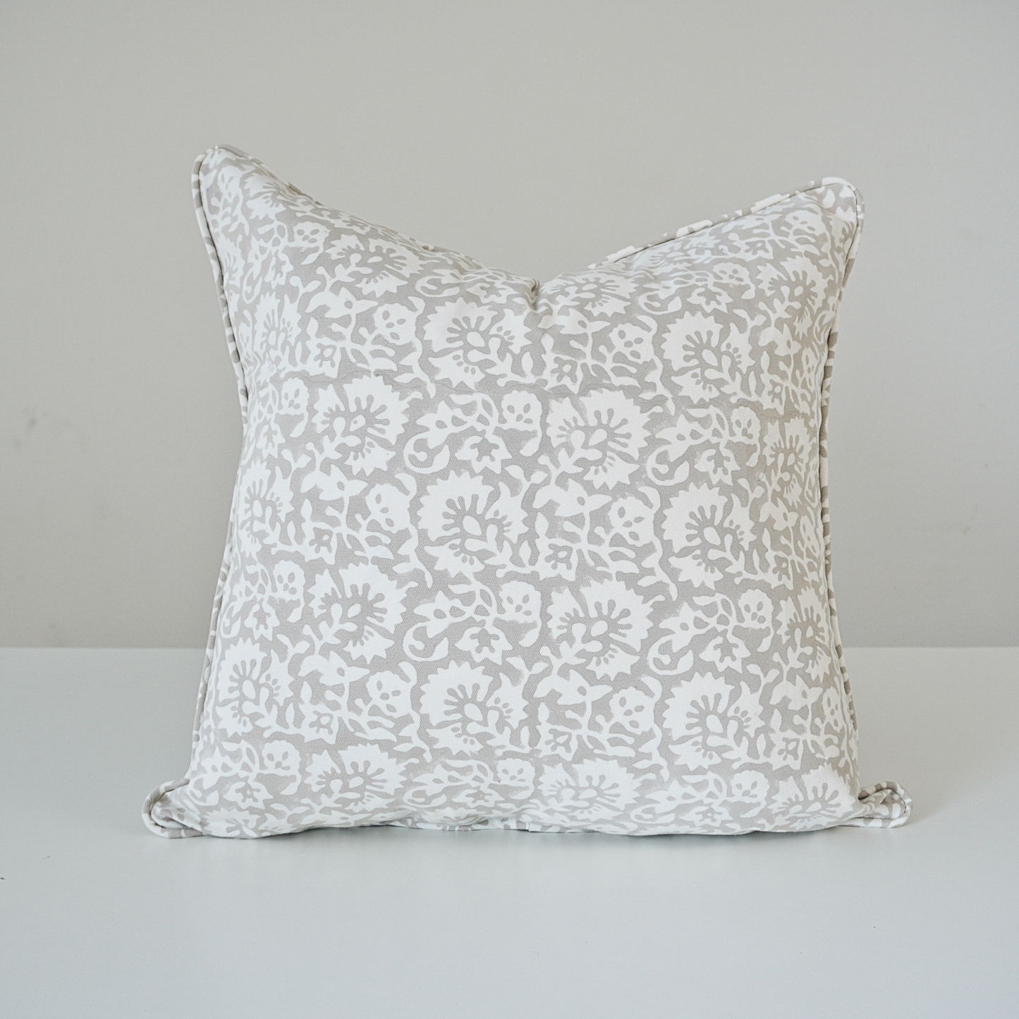 Square Fiora Muse 100% cotton block printed pillow cover. This artisan throw cushion features an intricate, dense floral botanical pattern in soft grey tones on a crisp white background with tailored piped edges. Fine handmade textile home decor.