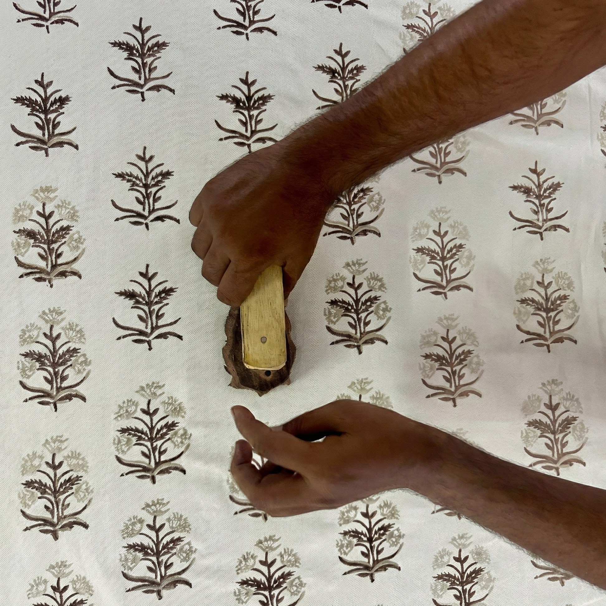 Artisan hands stamp an earthy brown floral pattern onto natural fabric with a carved wood block. This traditional hand-block printing process crafts our textiles, perfect for modern rustic farmhouse Canadian and USA home decor.