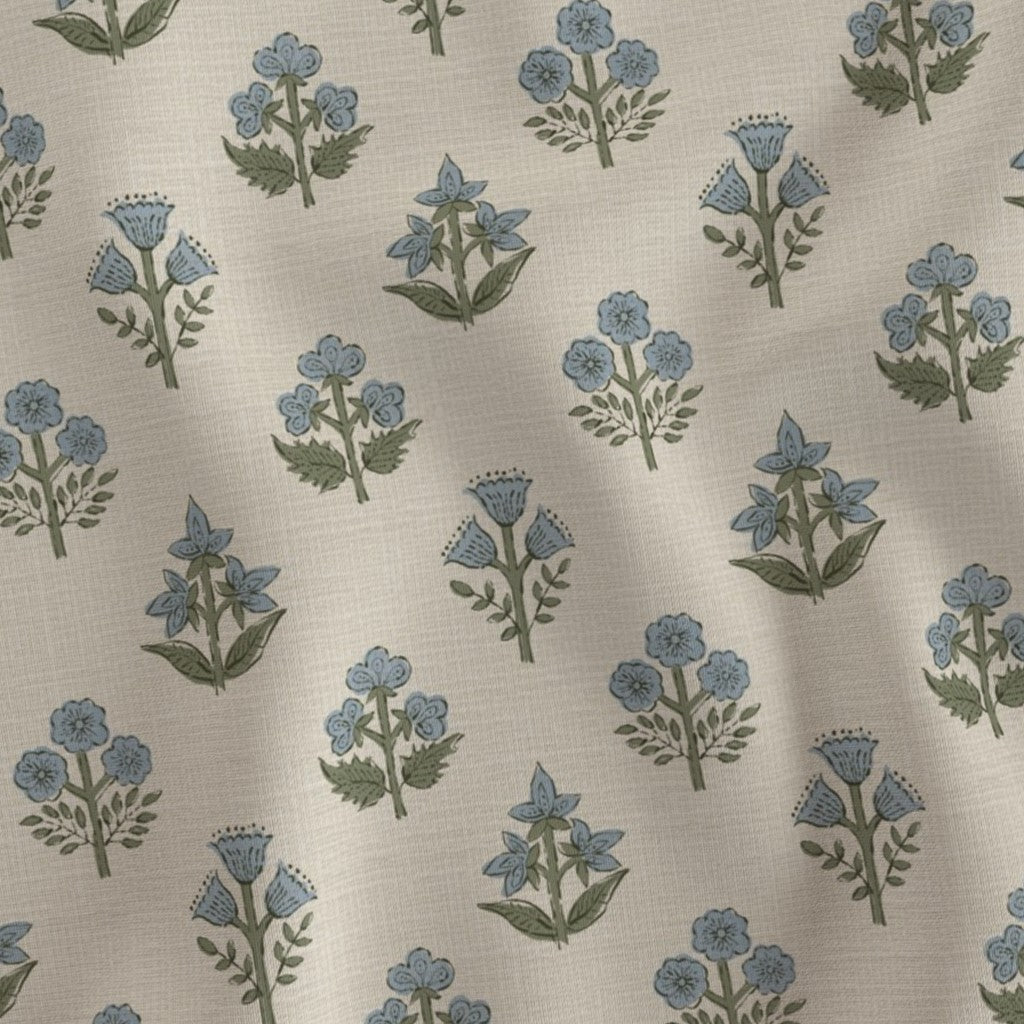 A close-up fabric swatch featuring a delicate light blue and green floral sprig block print pattern. Showcasing a natural textile texture, this artisanal print perfectly adds a cozy modern rustic farmhouse aesthetic to Canadian and USA home decor.