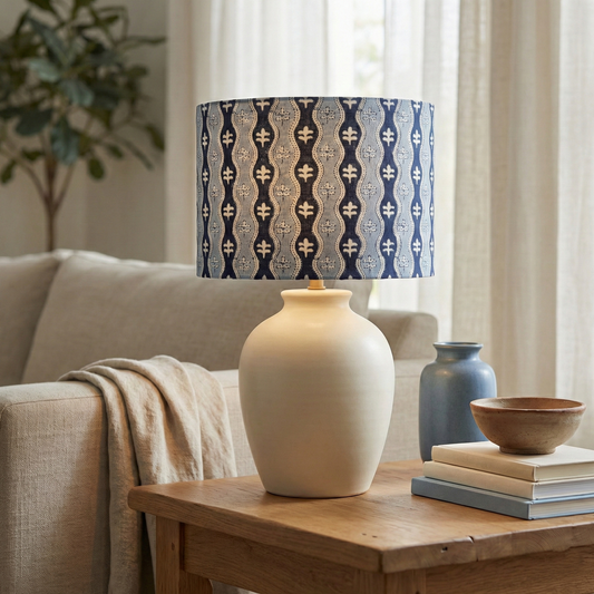 Decorative lamp with a patterned shade on a wooden table in a living room setting.