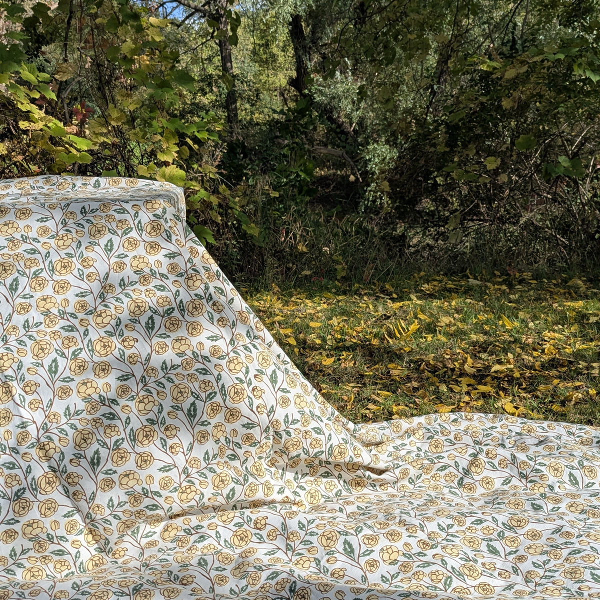 Block printed Floral patterned fabric with yellow flowers and green leaves on a white background
