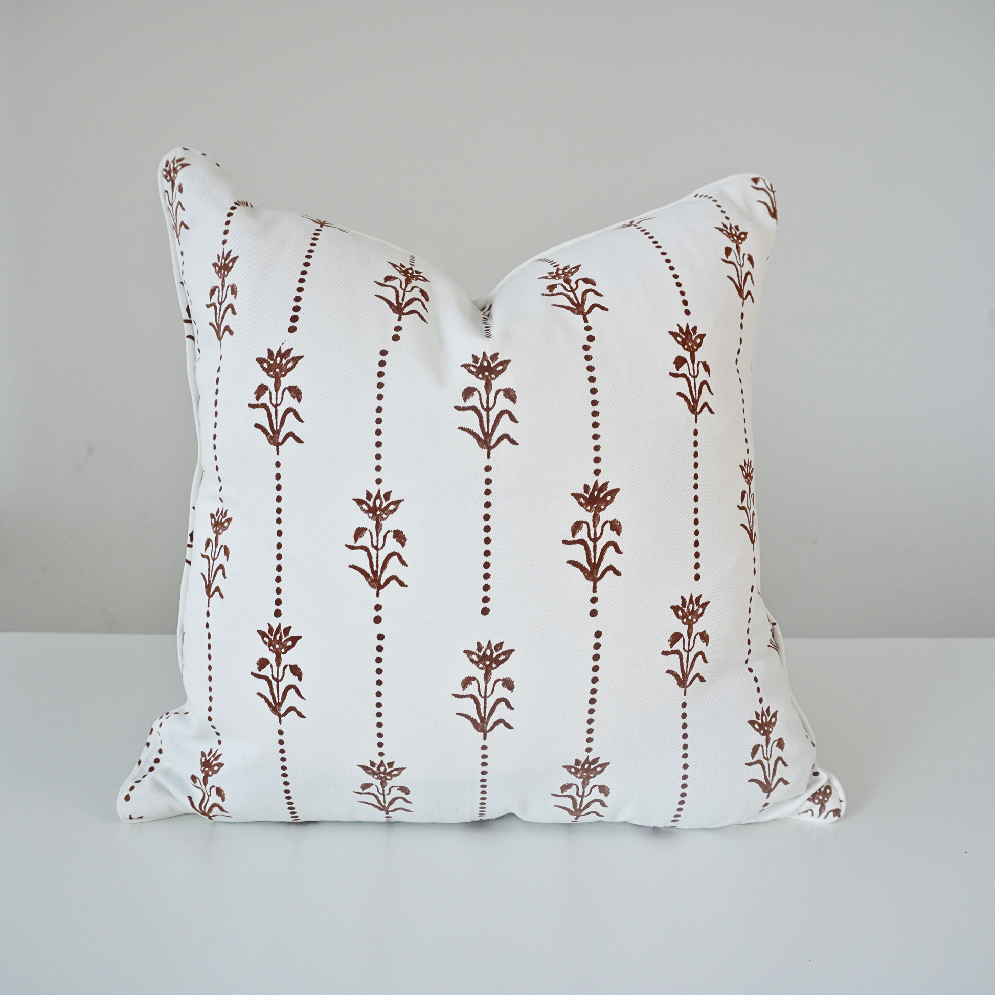 Square Reed Soil 100% cotton block printed pillow cover. This artisan throw cushion features a repeating earthy brown vertical dotted stripe and floral botanical motif on a crisp white background with tailored piped edges. Fine handmade textile home decor.