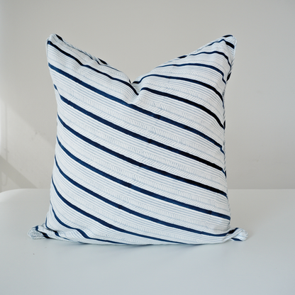 Studio product shot of a single Serere Frost cushion cover by Homeway Living, centered on a neutral background. Handcrafted from 100% cotton, it features diagonal navy blue and light grey stripes with subtle textured line details on a crisp white base. Finished with tailored piped edges, this block-printed artisan piece offers a clean, modern aesthetic perfect for coastal or Scandinavian decor.