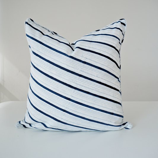 Studio product shot of a single Serere Frost cushion cover by Homeway Living, centered on a neutral background. Handcrafted from 100% cotton, it features diagonal navy blue and light grey stripes with subtle textured line details on a crisp white base. Finished with tailored piped edges, this block-printed artisan piece offers a clean, modern aesthetic perfect for coastal or Scandinavian decor.