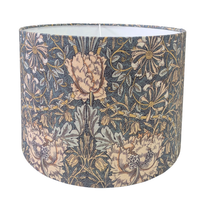 A drum lampshade featuring the classic William Morris Honeysuckle botanical pattern with peach flowers and green foliage on a dark background. This elegant vintage-style piece adds classic charm to a cozy modern rustic farmhouse aesthetic for both Canadian and USA home decor.