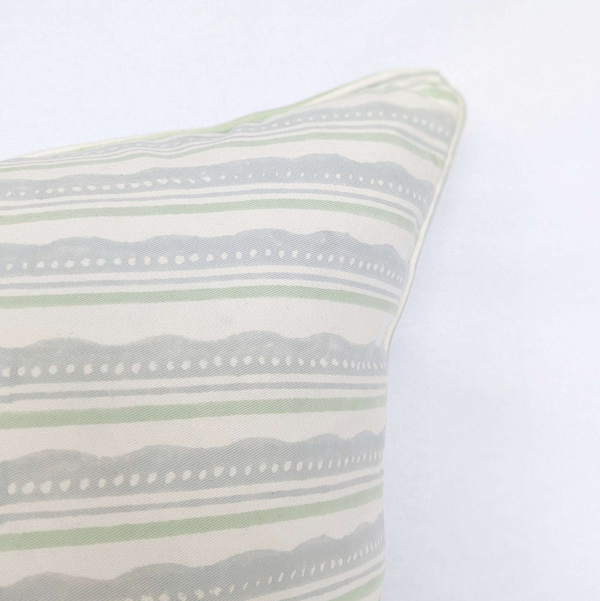 A close-up corner view of the "Amalfi Breeze" hand-block printed cushion, highlighting its refreshing sage green and light blue horizontal striped and wavy pattern on a crisp white background. This detail shot emphasizes the clean, piped edges, showcasing the quality of this handcrafted textile that perfectly adds a cozy modern rustic Canadian farmhouse aesthetic to any home decor.