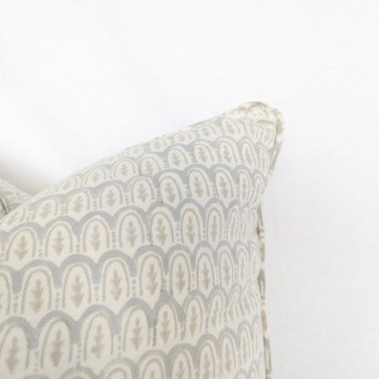 A close-up corner view of a light blue and neutral beige hand-block printed cushion cover, emphasizing the beautifully finished piped edge. The delicate, repeating scalloped arch motif highlights the intricate traditional artisanal craftsmanship involved in creating this textile. This square throw pillow is an ideal accent piece for adding a touch of warm, sophisticated modern rustic farmhouse style to both Canadian and USA interiors.