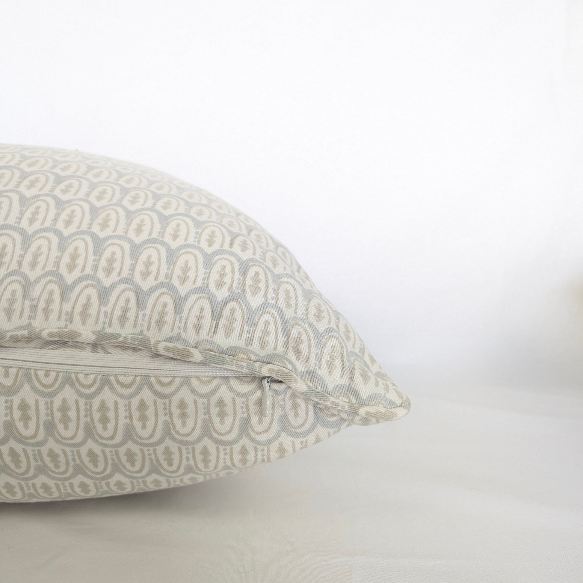Pale blue and beige hand-block printed cushion cover held up in bright natural light. The close-up showcases a delicate geometric pattern on natural cotton fabric, perfect for a modern Canadian rustic or farmhouse home decor aesthetic.