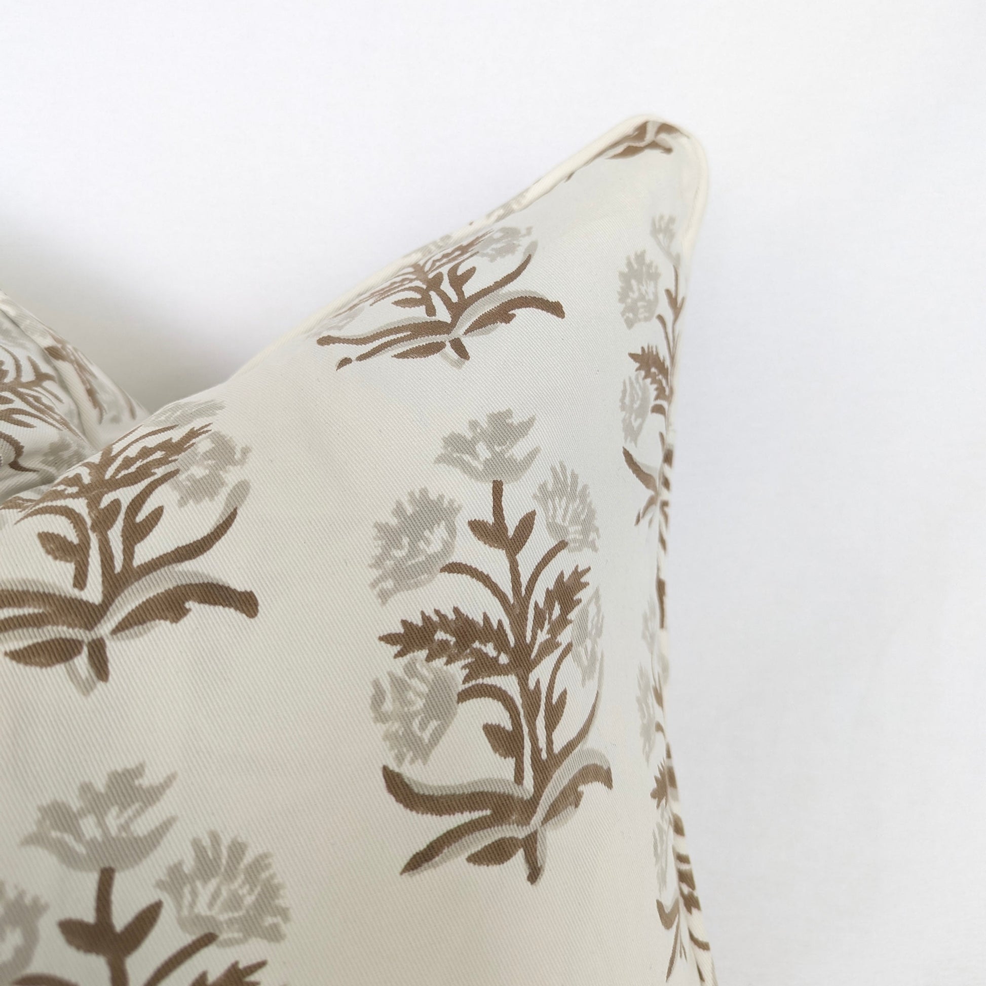 Close-up corner of an earthy brown and beige floral sprig hand-block printed cushion cover. Featuring elegant piped edges, this artisanal throw pillow perfectly accents Canadian and USA homes with a warm, cozy modern rustic farmhouse aesthetic.