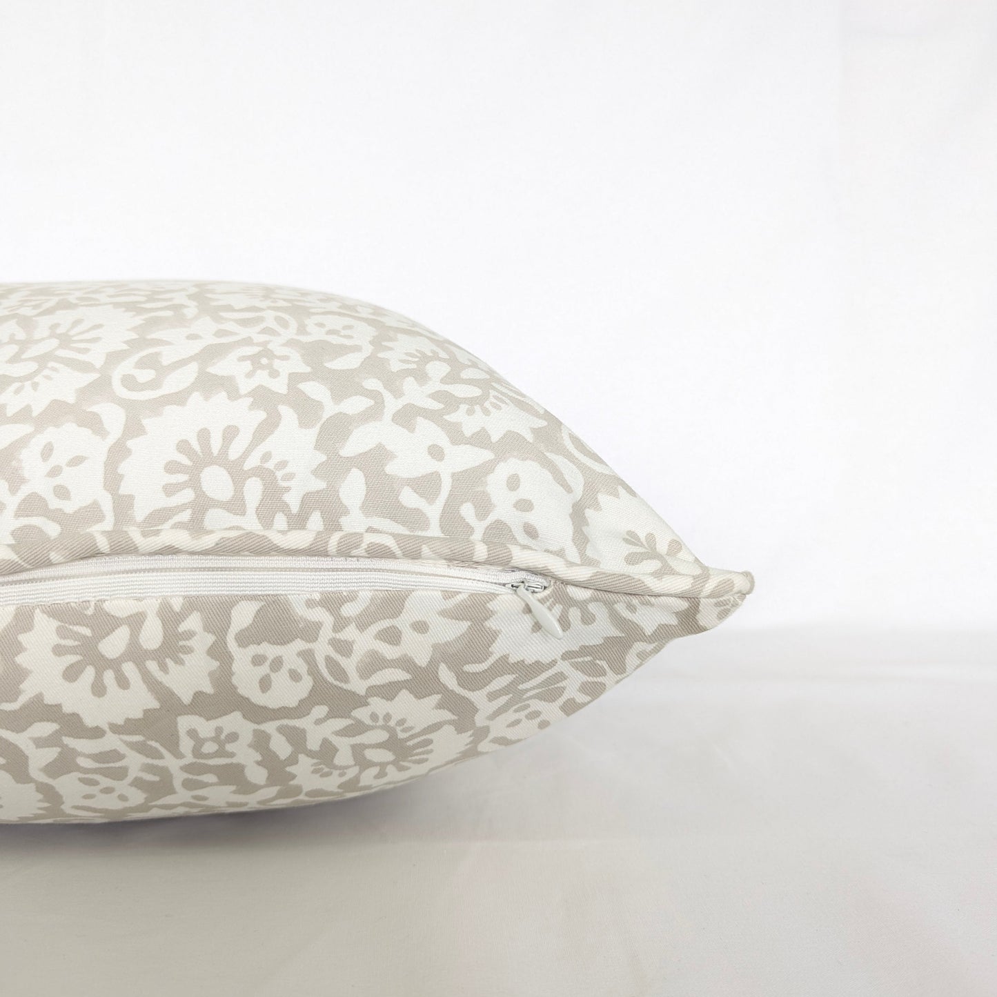 Side view of the Fiora Muse 100% cotton block printed pillow and cushion cover, highlighting the hidden zipper closure and tailored piped edge. The fabric features an intricate, dense floral botanical pattern in soft taupe and white. Fine handmade artisan textile home decor.