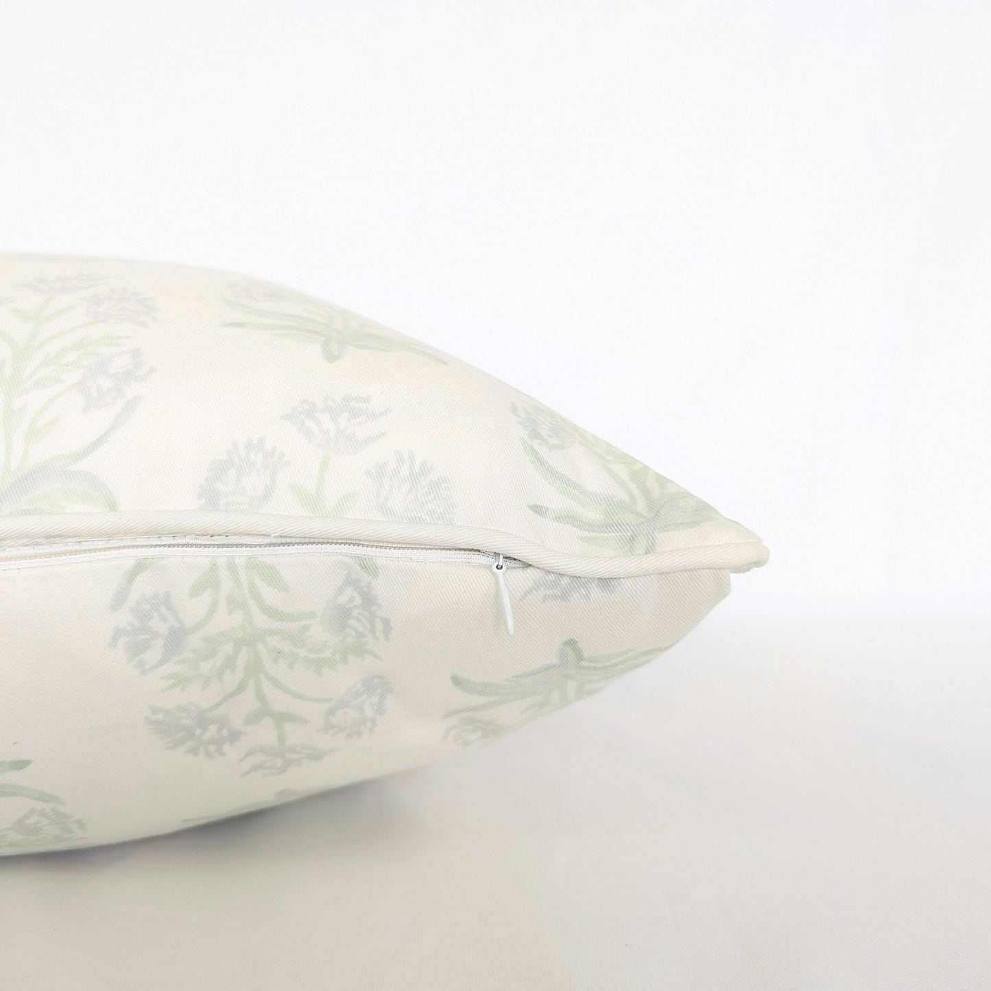 Close-up side view showing the hidden zipper closure and piped seam of the Jaipuri Breeze 100% cotton block printed pillow and cushion cover. Features a subtle sage green repeating floral stem motif on off-white fabric against a clean white background. Fine handmade artisan textile home decor.