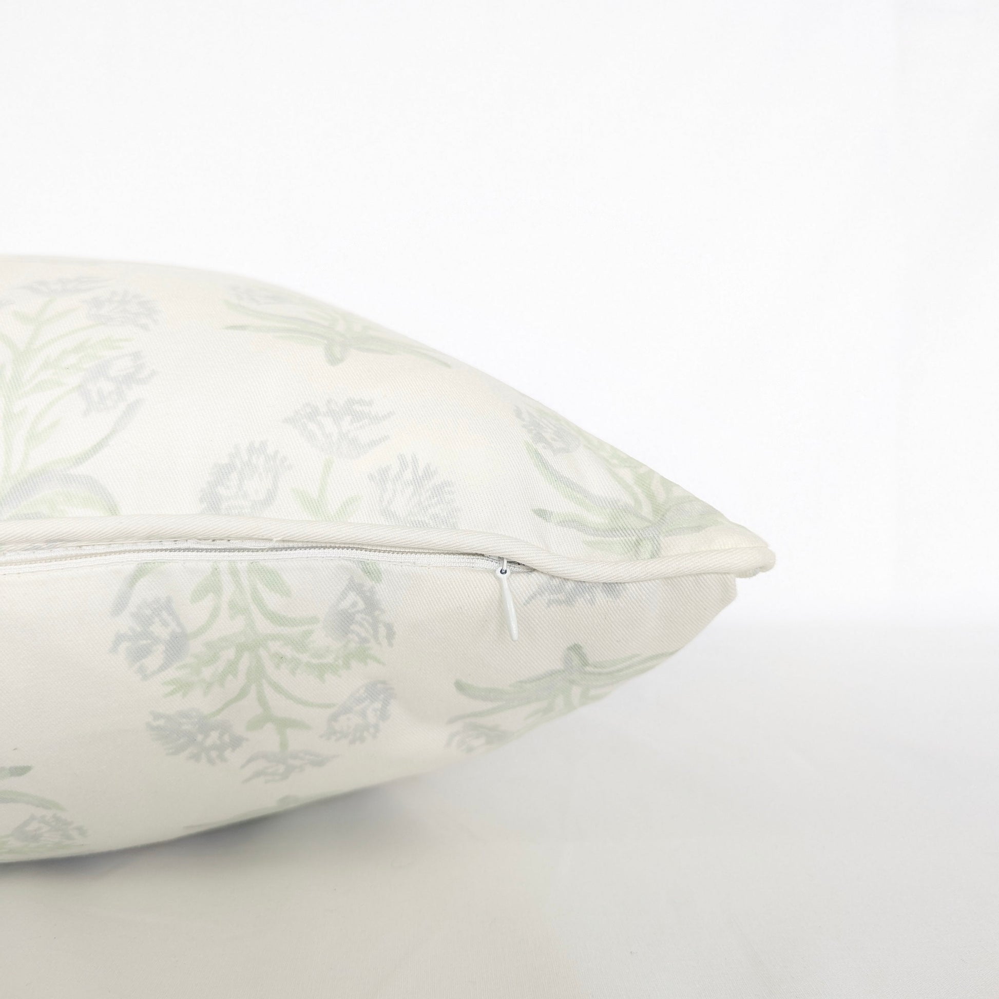 Close-up side view showing the hidden zipper closure and piped seam of the Jaipuri Breeze 100% cotton block printed pillow and cushion cover. Features a subtle sage green repeating floral stem motif on off-white fabric against a clean white background. Fine handmade artisan textile home decor.