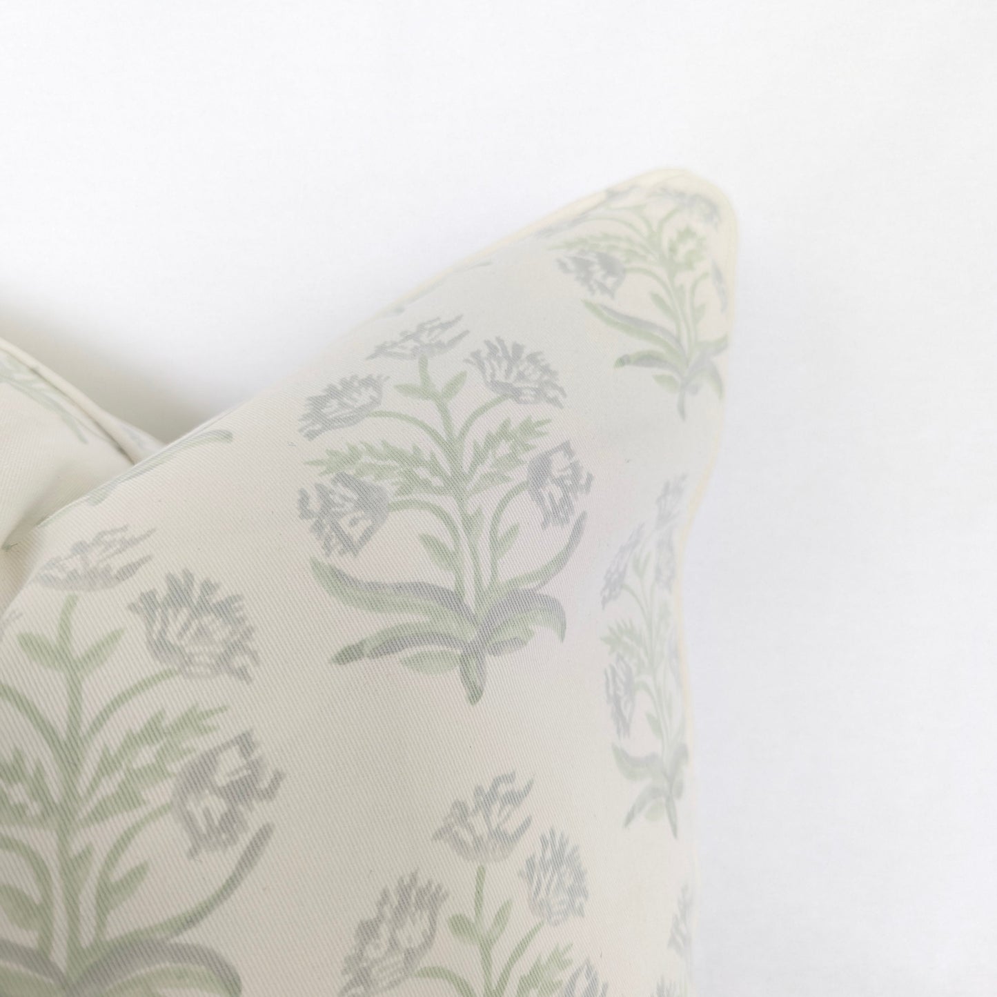 Close-up corner detail of the Jaipuri Breeze 100% cotton block printed pillow and cushion cover against a white background. Highlights the soft sage green repeating floral stem motif on off-white fabric with tailored piped edges. Fine handmade artisan textile home decor.