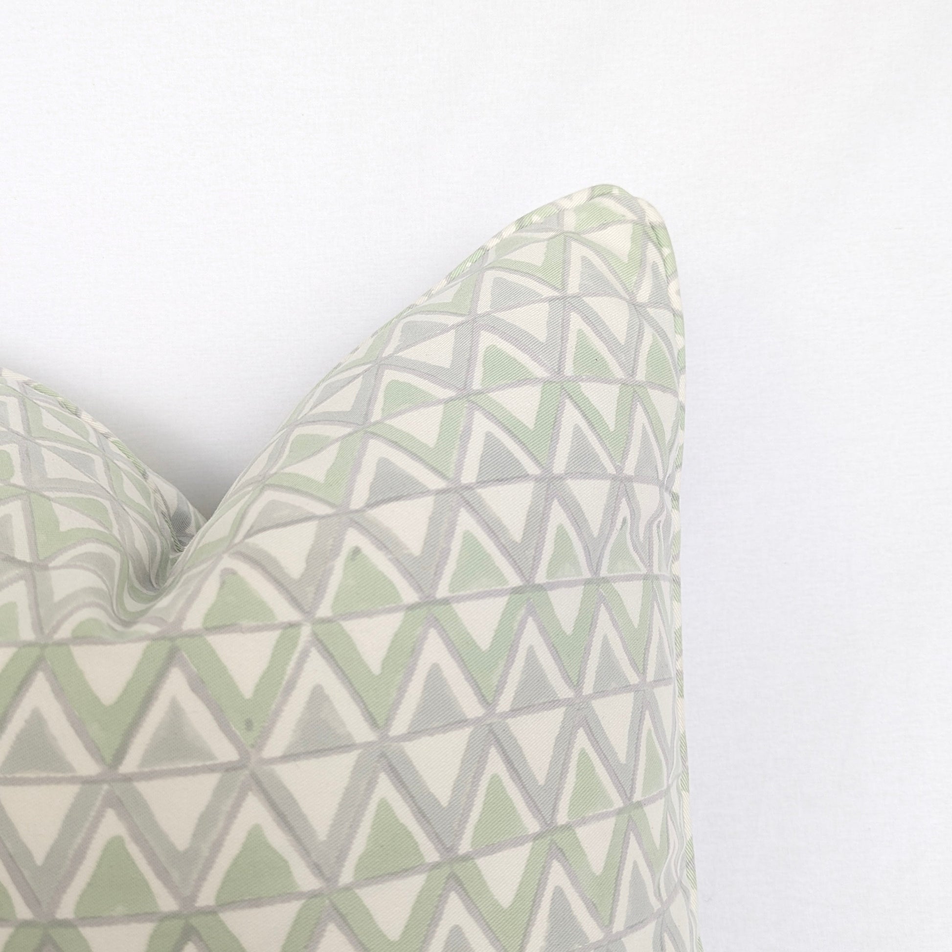 Close-up corner detail of the Moroccan Meadow Mist 100% cotton block printed pillow and cushion cover against a clean white background. Highlights the repeating geometric interlocking triangle pattern in soft meadow green and light grey with tailored piped edges. Fine handmade artisan textile home decor.