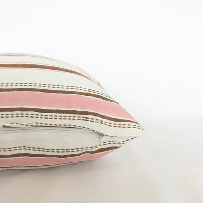 A close-up corner view of the hand-block printed Orai Soil cushion on a white background. This detailed shot highlights the tailored piped edges and the horizontal pattern of soft pink bands alternating with solid and dashed earthy brown stripes. This handcrafted textile adds a cozy modern rustic Canadian farmhouse aesthetic to your home decor.
