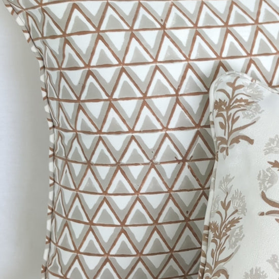 A close-up video detailing two hand-block printed cushion covers. An earthy brown geometric triangle pattern is styled beautifully beside a delicate floral sprig motif. This warm, artisanal textile pairing is perfect for adding a modern rustic farmhouse aesthetic to Canadian and USA homes.