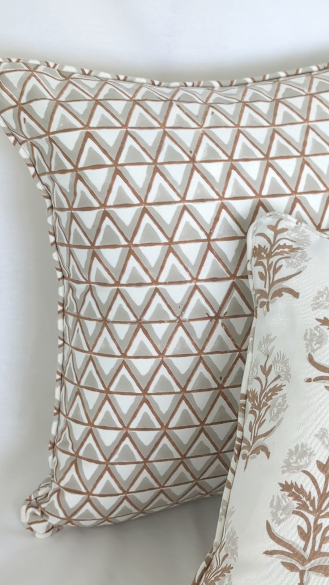 A close-up video detailing two hand-block printed cushion covers. An earthy brown geometric triangle pattern is styled beautifully beside a delicate floral sprig motif. This warm, artisanal textile pairing is perfect for adding a modern rustic farmhouse aesthetic to Canadian and USA homes.