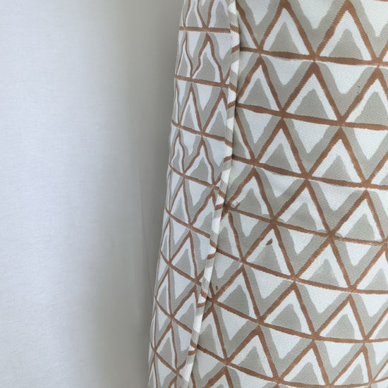 A short video showcasing a close-up of a hand-block printed cushion featuring an earthy tan and soft grey geometric triangle pattern on a cream background. Highlighting the side profile and piped edge, this beautifully handcrafted textile perfectly adds a cozy modern rustic Canadian farmhouse aesthetic to your home decor.