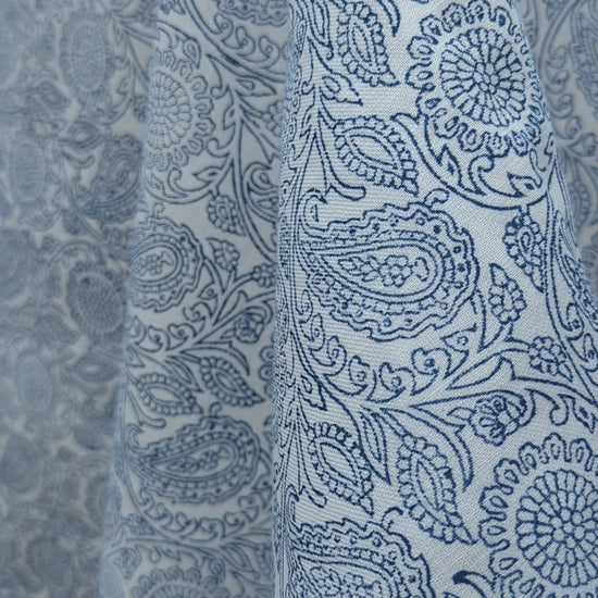 A close-up view of an artisan's hands firmly pressing a intricately carved wooden block onto fabric, demonstrating the traditional hand-block printing process. The textile reveals a striking blue and white geometric chevron pattern being stamped. This authentic craftsmanship highlights the quality of these handmade textiles, perfectly suited for adding a cozy modern rustic Canadian farmhouse aesthetic to your home decor.