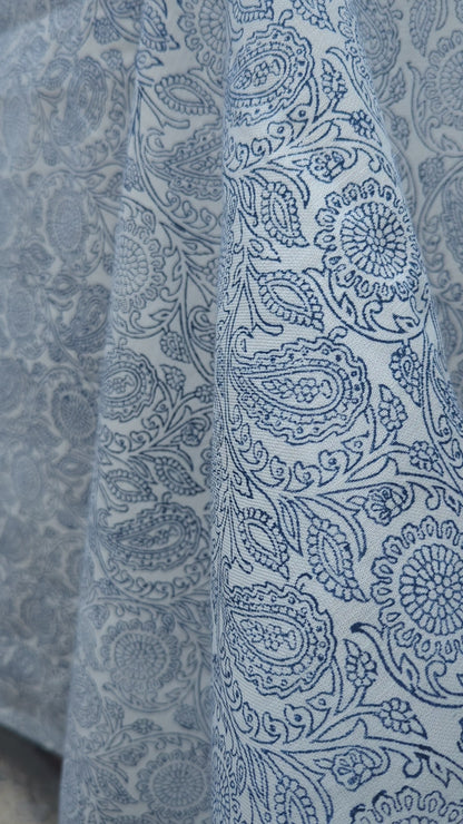 A close-up view of an artisan's hands firmly pressing a intricately carved wooden block onto fabric, demonstrating the traditional hand-block printing process. The textile reveals a striking blue and white geometric chevron pattern being stamped. This authentic craftsmanship highlights the quality of these handmade textiles, perfectly suited for adding a cozy modern rustic Canadian farmhouse aesthetic to your home decor.