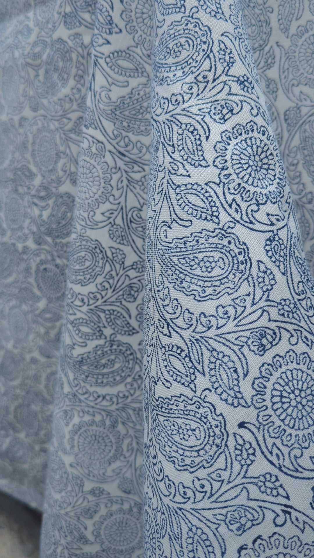 A close-up view of an artisan's hands firmly pressing a intricately carved wooden block onto fabric, demonstrating the traditional hand-block printing process. The textile reveals a striking blue and white geometric chevron pattern being stamped. This authentic craftsmanship highlights the quality of these handmade textiles, perfectly suited for adding a cozy modern rustic Canadian farmhouse aesthetic to your home decor.
