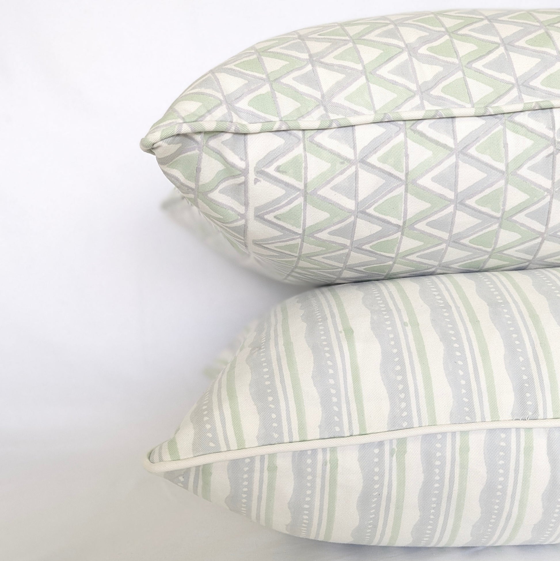 A studio shot of a curated trio of hand-block printed cushion covers in refreshing, airy tones of sage green and soft blue on crisp white fabric. The collection features an artful mix of a geometric triangle pattern, a horizontal striped and wavy design, and a delicate floral motif, perfectly adding a cozy modern rustic Canadian farmhouse aesthetic to any home decor.